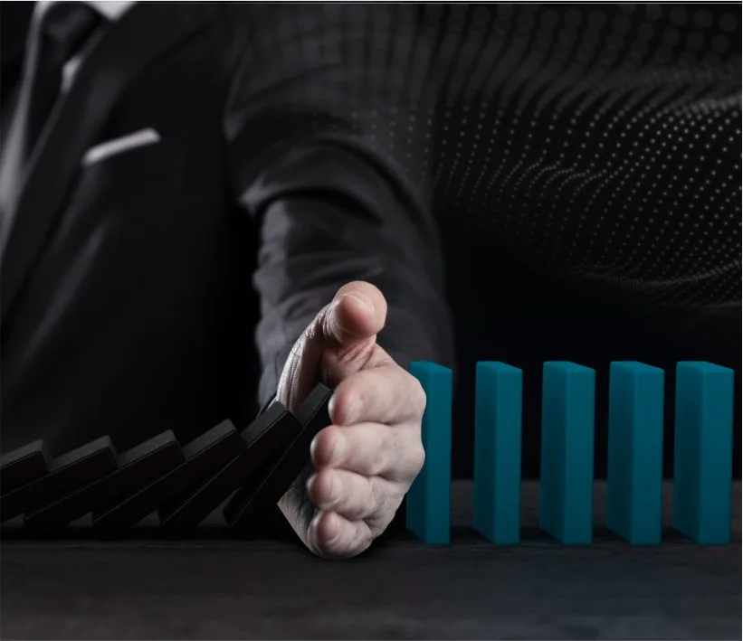 Profissional interrompendo uma sequência de dominós para representar a mitigação de riscos