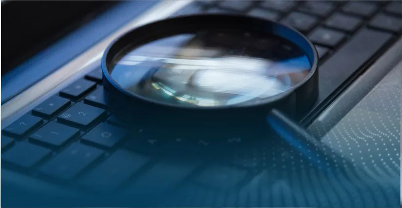 Lupa sobre um teclado representando a análise de processos na auditoria interna